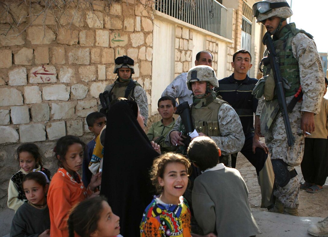 HAQLANIYAH, Iraq (Nov. 30, 2005)  - Staff Sgt. Joshua D. Vandiver (center), a team chief for 6th Civil Affairs Group, Detachment Two, Team 3 and the team's interpreter Haydar "Mike" Al-Assadi (right) talk with a local woman as Cpl. Luis O. Jones (left), a team member, provides security during a assessment patrol here Nov. 30. The team goes on these patrols numerous times a week to talk with people and give money to repair damages to their property. (Official Marine Corps photo by Cpl. Adam C. Schnell)