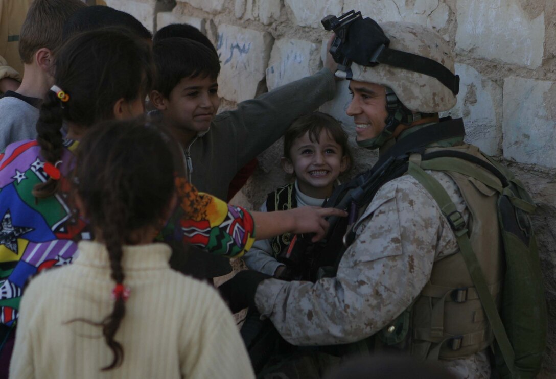 HAQLANIYAH, Iraq (Nov. 30, 2005)  - Corporal Luis O. Jones, a team non-commissioned officer for 6th Civil Affairs Group, Detachment Two, Team 3, plays with kids while on an assessment patrol here Nov. 30. Jones, a Daytona Beach, Fla. native, is one of five members of the team that operates in the city to help the residents rebuild their communities and improve the lives of the people. (Official Marine Corps photo by Cpl. Adam C. Schnell)