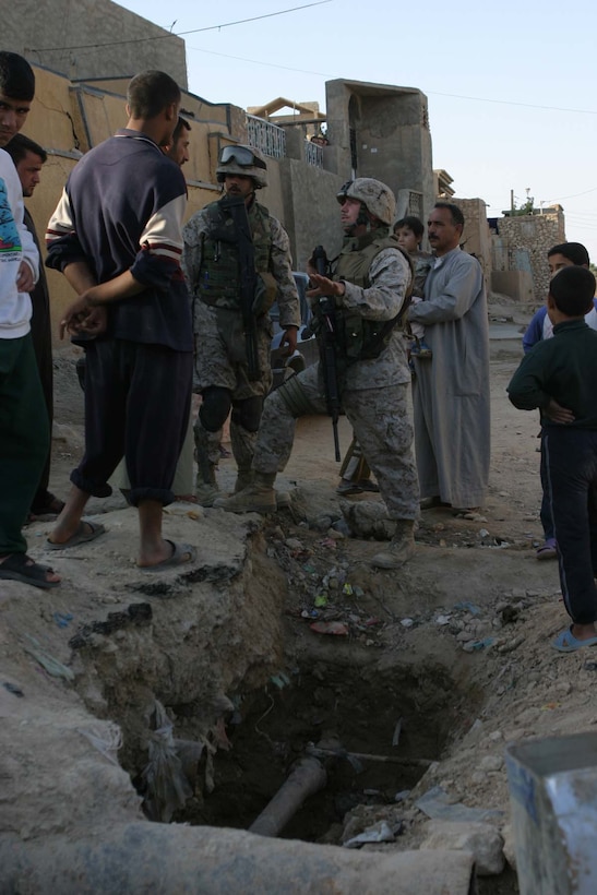 HAQLANIYAH, Iraq (Nov. 30, 2005)  - Staff Sgt. Joshua D. Vandiver, a team chief for 6th Civil Affairs Group, Detachment Two, Team Three, with the help of the team's interpreter Haydar "Mike" Al-Assadi, talk with residents about a leaking water pipe in the city here Nov. 30 The team operates in the city here to assist the residents by helping to repair buildings and water pipes to improve the lives of the people. (Official Marine Corps photo by Cpl. Adam C. Schnell)