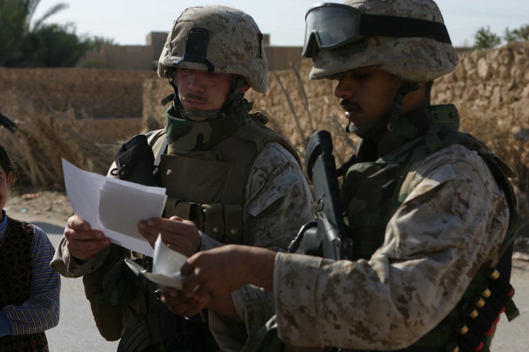 HAQLANIYAH, Iraq (Nov. 30, 2005)  - Staff Sgt. Joshua D. Vandiver (Left), a team chief for 6th Civil Affairs Group, Detachment Two, Team 3, and the team's interpreter Haydar "Mike" Al-Assadi, look over pictures of damages to a resident's house while on a assessment patrol here Nov. 30. The two-team members are part of a five-man team that operates in the city here to help the residents rebuild their city to improve the lives of the people. (Official Marine Corps photo by Cpl. Adam C. Schnell)