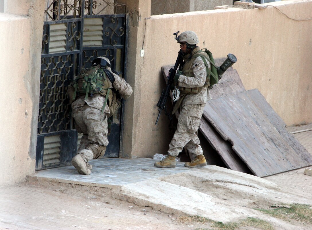 AR RAMADI, Iraq (November 30, 2005) - Two Marines from 3rd Battalion, 7th Marine Regiment, open a gate in order to clear a building during Taskforce Block Party Six Nov. 30. Photo by Cpl. Shane Suzuki