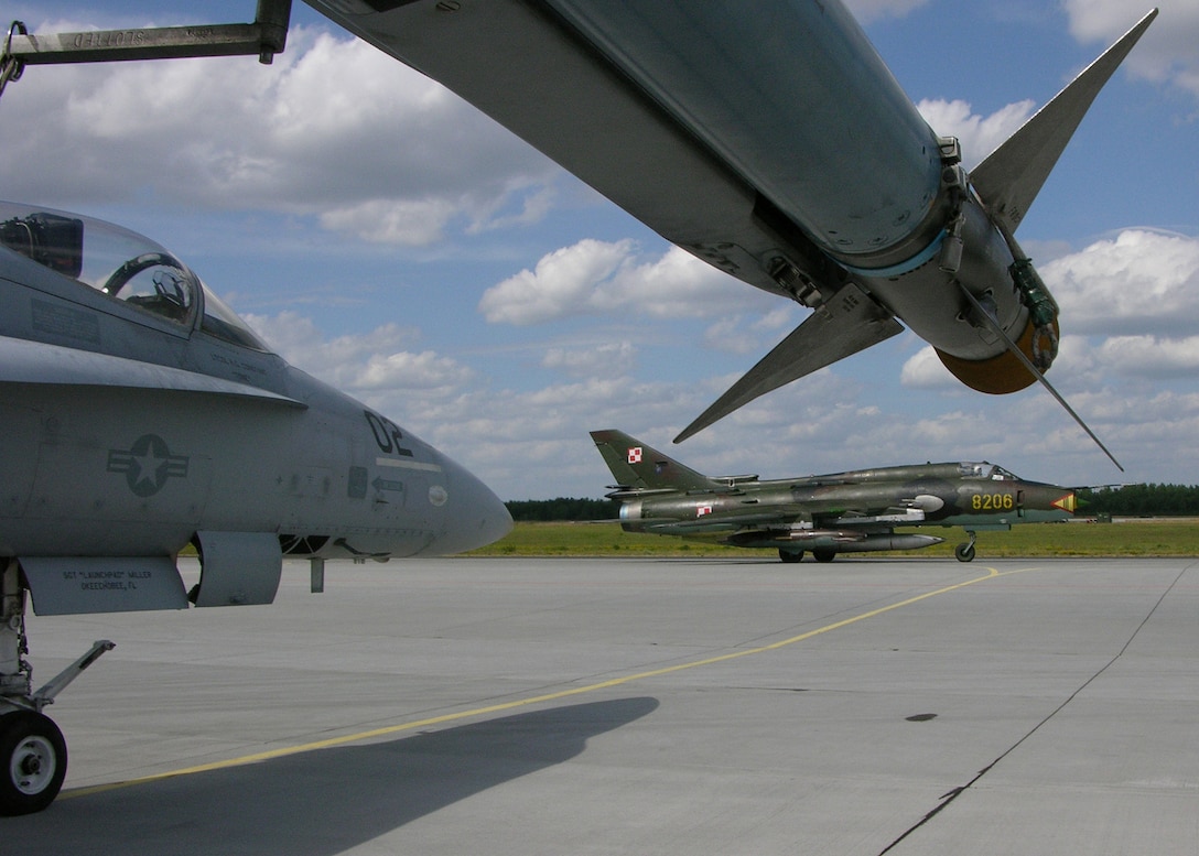 31st AIR BASE, Poznan, Poland -- A Polish MiG-21 taxis down the runway past an American F/A 18 to prepare for takeoff during Exercise Clean Hunter 2005.   The NATO exercise brought together 13 nations to exercise the conduct of offensive, defensive air maneuvers in support of large-scale operations.