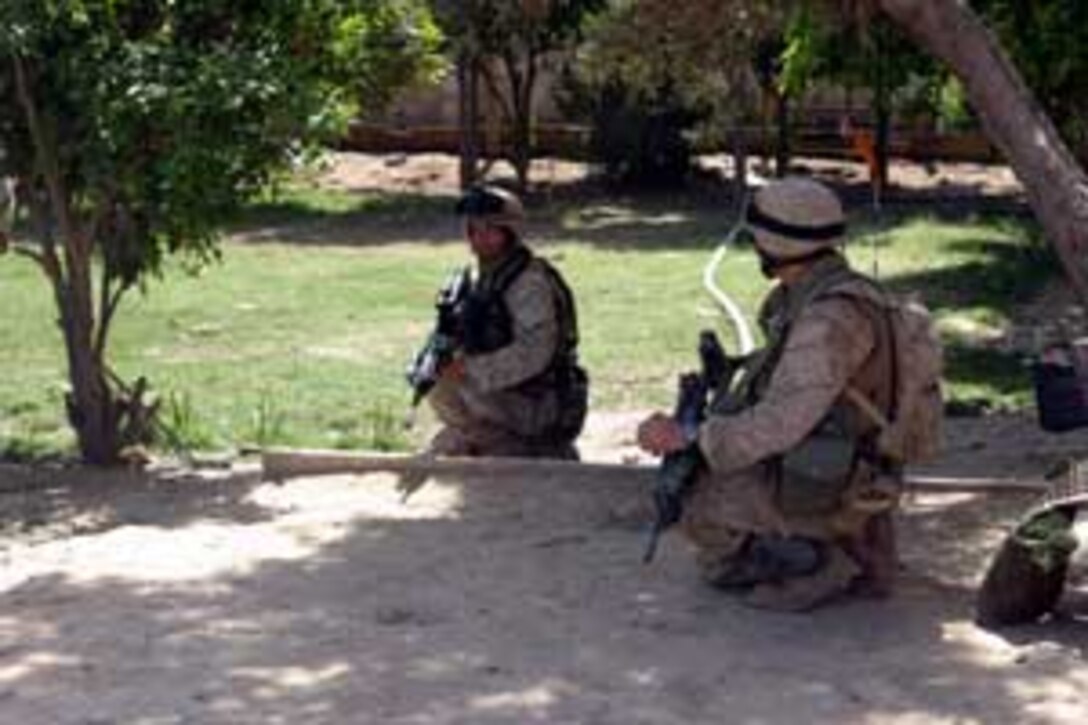 Lance Cpls. Matthew K. Baughman, 22, a native of Hutchinson, Kan., and Dan J. Hayes, 21, a native of Elkhart, Ind., both infantry men with A Co., Battalion Landing Team 1/1, take a knee and wait for their next command during a patrol here. BLT 1/1, attached to the 15th Marine Expeditionary Unit (Special Operations Capable), is currently conducting security and stabilization operations in the Greater Baghdad area.