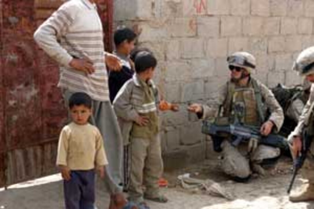 Lance Cpl. Dan J. Hayes, 21, an infantry man with Battalion Landing Team 1/1, and a native of Elkhart, Ind., gives a piece of candy to an Iraqi child during a patrol here. BLT 1/1, attached to the 15th Marine Expeditionary Unit (Special Operations Capable), is currently conducting security and stabilization operations in the Greater Baghdad area.