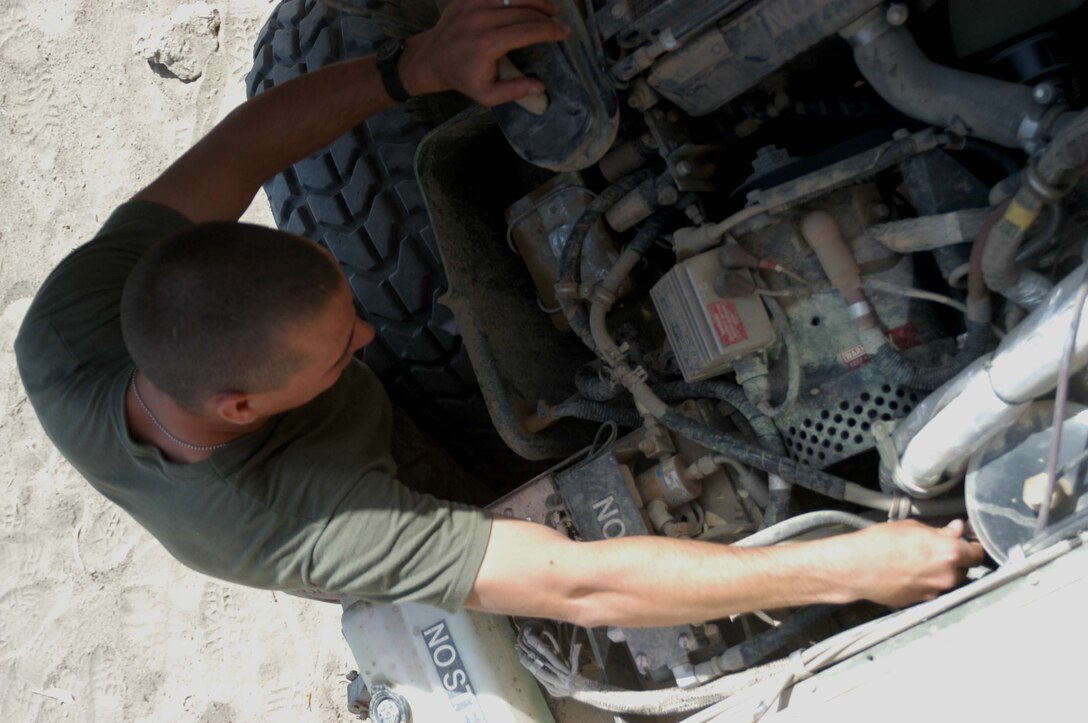CAMP HURRICANE POINT, Ar Ramamdi, Iraq (March 31, 2005) -Twenty-seven-year-old Pfc. David S. Johnson of Newbaltimore, Mich., a motor transportation mechanic with Headquarters and Service Company, 1st Battalion, 5th Marines, checks the oil of a humvee brought to his garage. Johnson and Cpl. Michalson Bahe, who's also a motor T mechanic, boast a 24-hour turn around time on all the vehicles they work on. The two grease monkeys are responsible for maintaining and repairing 90 of the infantry battalion's vehicles. They stay on call during the night and routinely find themselves burning the midnight oil fixing humvees and 7-tons at their shop. Photo by Cpl. Tom Sloan
