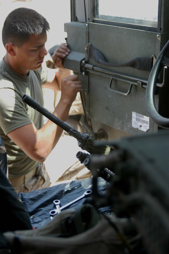 CAMP HURRICANE POINT, Ar Ramamdi, Iraq (March 31, 2005) -Twenty-one-year-old Cpl. Michalson Bahe of Casa Grande, Ariz., a motor transportation mechanic with Headquarters and Service Company, 1st Battalion, 5th Marines, repairs the latch on a door of a humvee brought to his garage by a Marine with Weapons Company who said it was getting difficult to open. Bahe and Pfc. David S. Johnson, who's also a motor T mechanic, boast a 24-hour turn around time on all the vehicles they work on. The two grease monkeys are responsible for maintaining and repairing 90 of the infantry battalion's vehicles. They stay on call during the night and routinely find themselves burning the midnight oil fixing humvees and 7-tons at their shop. Photo by Cpl. Tom Sloan