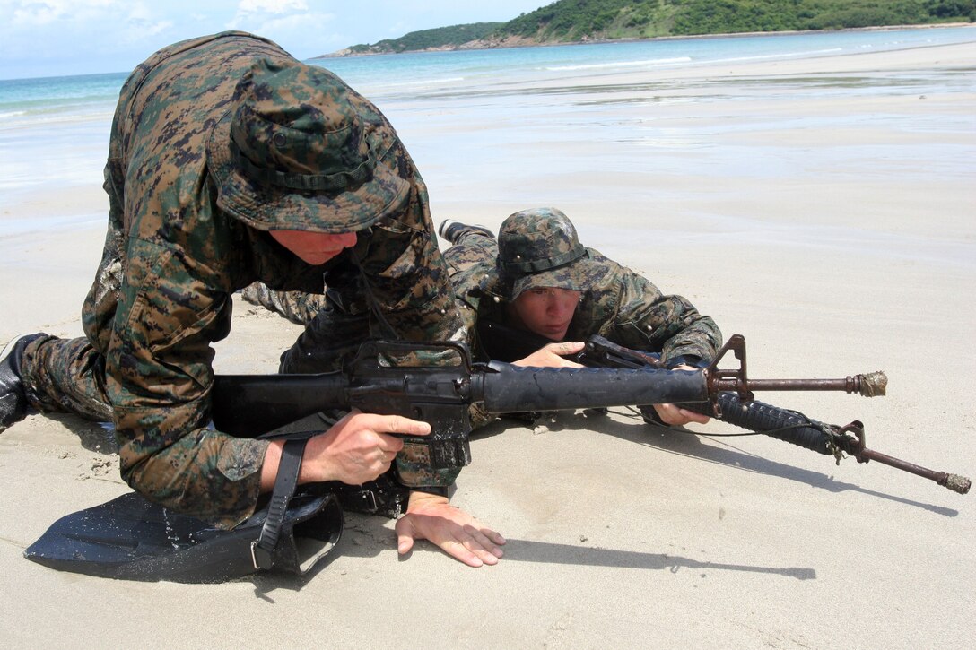 Pfc. Dustin F. Delligatti (left) rushes down Had Yao Beach while Lance Cpl. Ryan Hanson provides security June 20 during a scout swimmer exercise with the Royal Thai Marine Corps. The exercise was part of Cooperation Afloat Readiness and Training 2007, an annual series of bilateral, maritime exercises between the United States and five Southeast Asian nations. Delligatti and Hanson are scout swimmers with III Marine Expeditionary Force?s Special Operations Training Group.