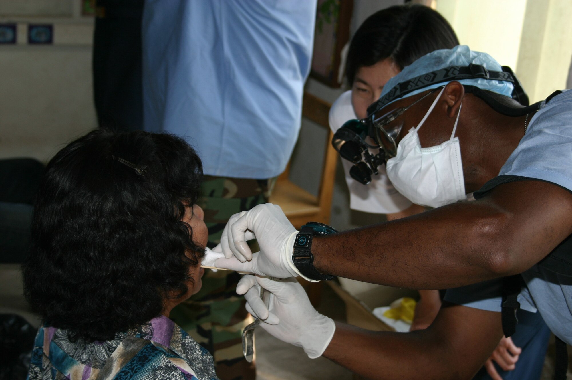 KORAT, Thailand -- Maj. (Dr.) John Kersey performs a dental procedure on a patient at a school here Jan 29.  Military medical teams from the Air Force, Navy, Thailand and Singapore are easing suffering by giving ocular and dental care to local people.  Dr. Kersey is a comprehensive dentist from the 18th Dental Squadron at Kadena Air Base, Japan.  (U.S. Air Force photo by 2nd. Lt. Ben Sakrisson)
