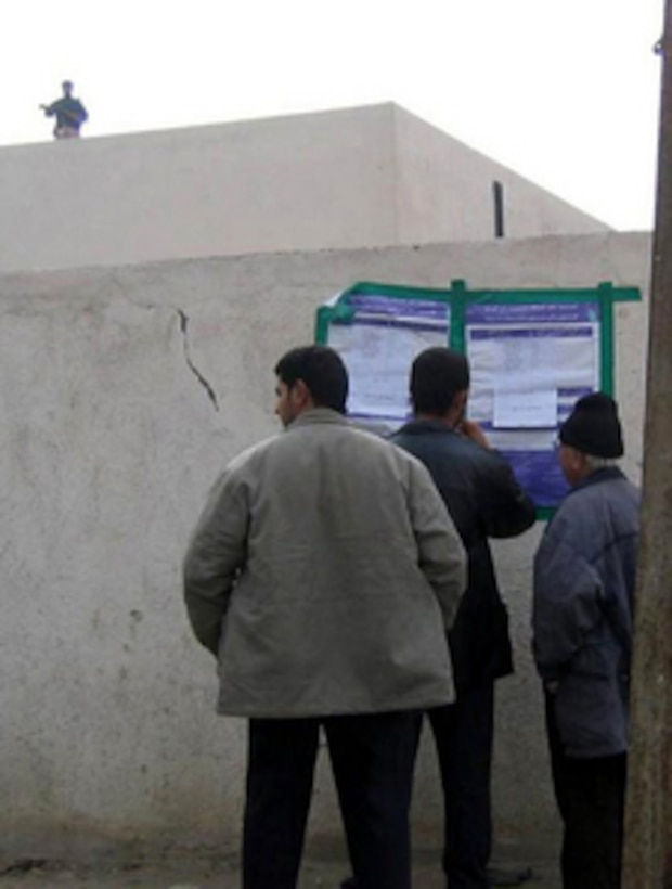 Iraqi residents of Baghdad's Nine Nissan district read polling instructions outside a local polling site as they prepare to cast their ballots on Jan. 30, 2005, during Iraq's first free election in over 50 years. 