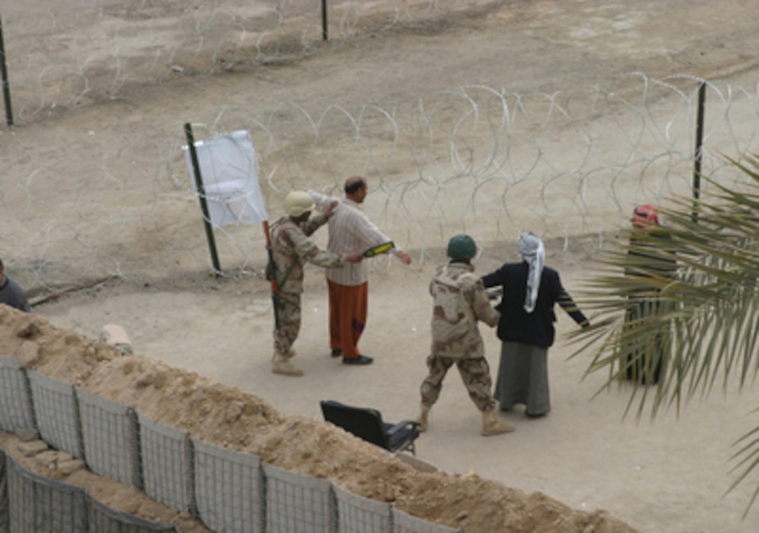 Iraqi service members use hand-held metal detectors to search citizens entering the Jolan Park polling station in Fallujah, Iraq, as they prepare to cast their ballots on Jan. 30, 2005. Iraqi voters are being searched with metal detectors to ensure that no weapons or explosives are carried into polling stations. Millions of Iraqis throughout the country are participating in Iraq's first free election in over 50 years. 