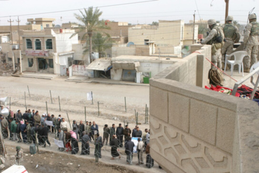 Members of the Iraqi Police and U.S. Marines watch over the lines of Iraqi citizens waiting to cast their ballots at a polling station in Jolan Park in Fallujah, Iraq, on Jan. 30, 2005. Millions of Iraqis throughout the country are participating in Iraq's first free election in over 50 years. The Marines keeping watch at this polling station are from India Company, 3rd Battalion, 5th Marine Regiment of the 1st Marine Division. 