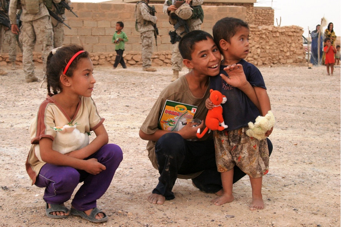 AL ANBAR PROVINCE, Iraq ? Iraqi children smile after receiving toys from members of the 5th Civil Affairs Group, 2nd Marine Division.  Marines and Sailors of Marine Aircraft Group-26 have gathered more than 15,000 items that members of 5th CAG have delivered to the needy in the community.  The items come from many sharing supporters in the United States.