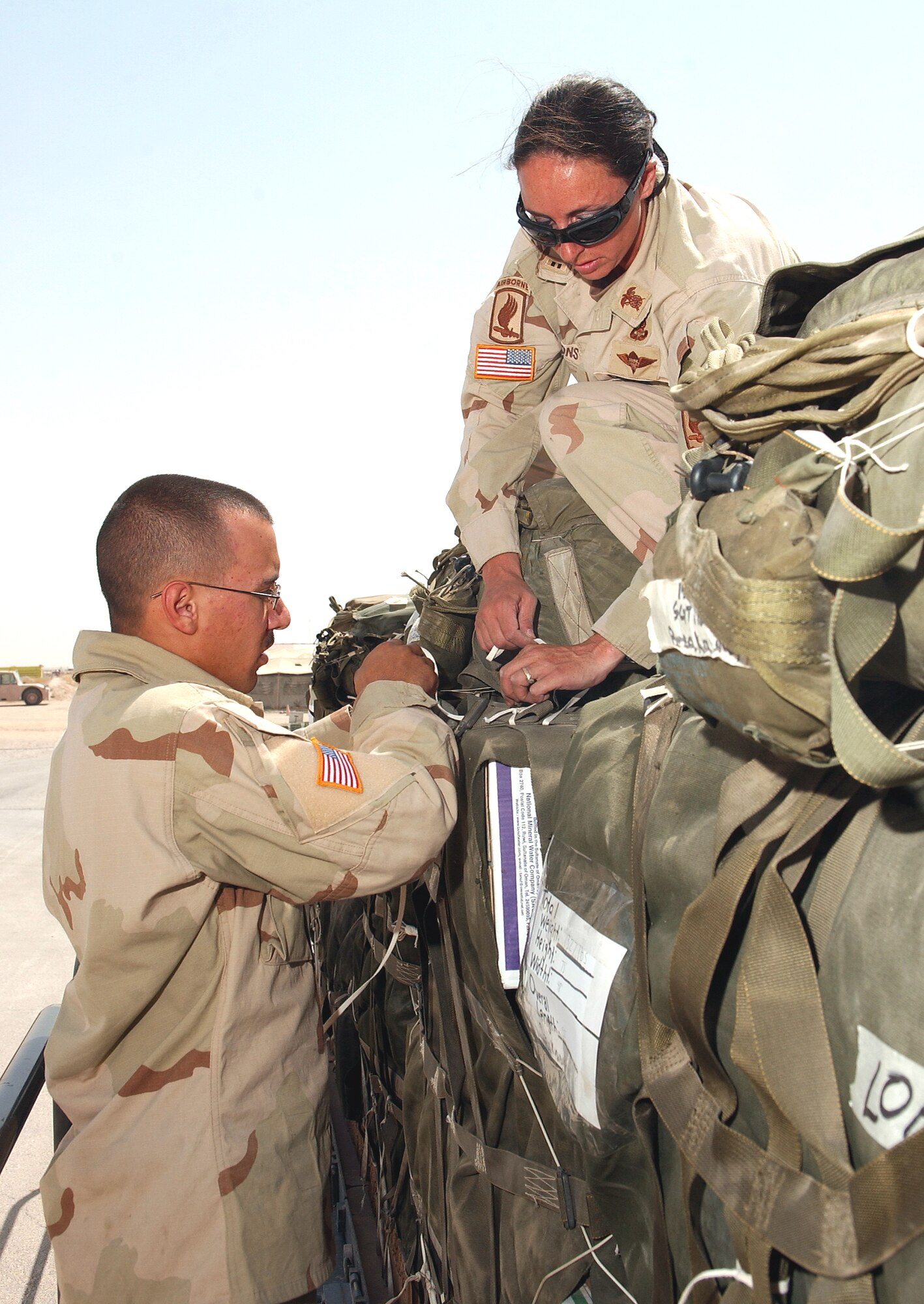 SOUTHWEST ASIA -- Army Chief Warrant Officer 2nd Class Eugenia Emmons (right) and Private 1st Class Isiah Rodriguez make final checks on a container delivery system's parachute rigging before loading it onto a C-130J Hercules for airdrop into Afghanistan June 30.  The mission was the first-ever combat airdrop for the new J-model transport.  It supported an Army air assistance request for troop re-supply and civic assistance to be dropped in the vicinity of Kandahar, Afghanistan.  (U.S. Air Force photo by Airman 1st Class Desiree Hayden)