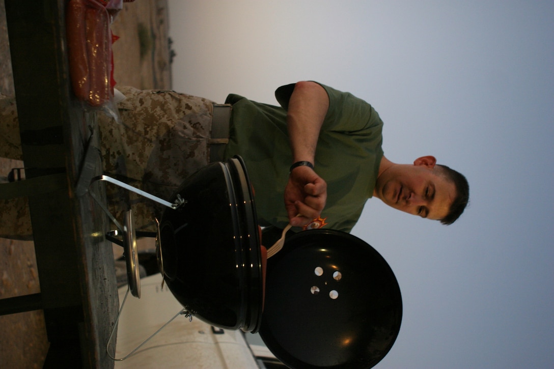 CAMP TAQADDUM, Iraq -- Gunnery Sgt. Anthony J. Masucci, a Fairfield, Ohio, native and G-4 section chief grills hot dogs during a recent softball game.  Masucci and other G-4 Marines are regular fans at Headquarters and Service Battalion's softball games.