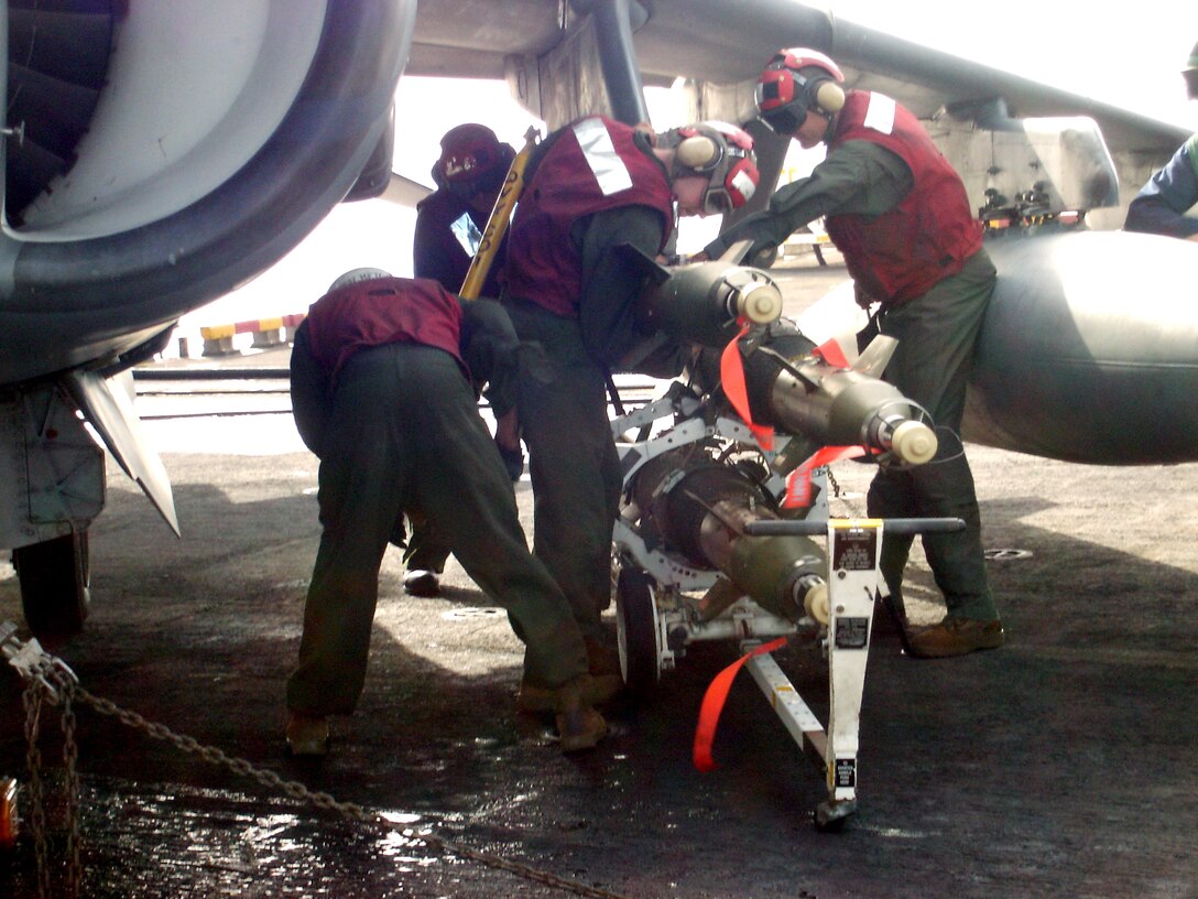 A team from the ordnance division of Marine Medium Helicopter Squadron-162, 26th Marine Expeditionary Unit (Special Operations Capable), loads GBU-12 bombs on an AV-8B Harrier aboard USS Kearsarge. The 26th MEU, theater reserve for U.S. Central Command, is embarked aboard ships of the Kearsarge Strike Group in the northern Arabian Gulf. (Photo courtesy of the ordnance division)