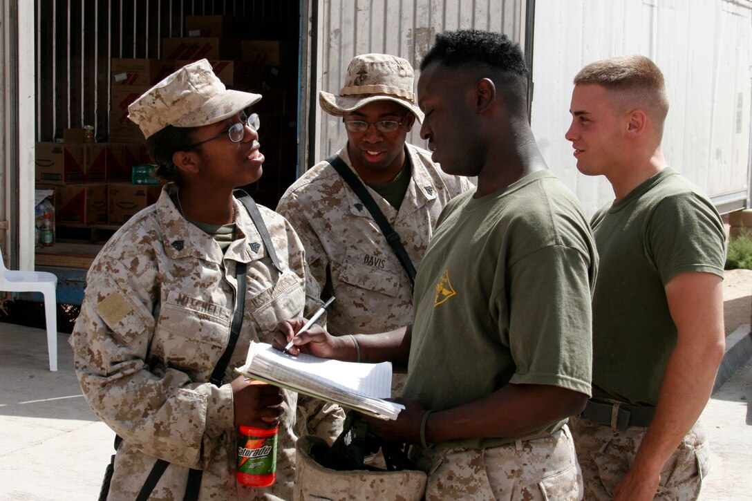 AL ASAD, Iraq ? Sergeants Sharina Emily Mitchell and Gregory Andre Davis, food service specialists, assist Sgt. Quincy Pippen, assistant chief cook at the Marine Wing Support Squadron 271 field mess and Woodbridge, Va., native, and Lance Cpl. Dennis Ruff, MWSS-271 motor transport operator from Huntsville, Ark., with signing out containers with food for the satellite dining facility in the MWSS-271 compound July 5.  Mitchell, from Cheverly, Md., and Davis, from Harrisburg, Pa., supervise the preparation of meals and assist with issuing food out for those whose busy schedule doesn?t give them a chance to eat at the mess hall.