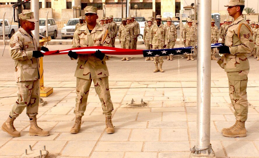 BAGHDAD, Iraq -- (From left) Staff Sgt. Aldrin Saguin, Tech. Sgt. Joseph Romero and Staff Sgt. Steve Gutierrez fold the flag during a retreat ceremony here celebrating Independence Day. The Airmen are honor guard members and are assigned to the 447th Expeditionary Civil Engineer Squadron here. They are deployed from Kadena Air Base, Japan. (U.S. Air Force photo by Tech. Sgt. Brian Davidson)  