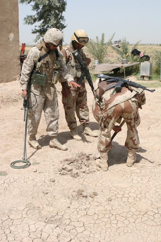 Corporal Khanh Pham, 23, combat engineer, CLB-8, 2nd Force Service Support Group (forward), watches an Iraqi soldier dig in a hot spot detected by his metal detector. Pham, who is attached to Echo Company, Iraqi Interdiction Force Platoon, 3rd Reconnaissance Battalion, 2nd Marine Division, supports the battalion with improvised explosive device, mine and weapon cache sweeps.