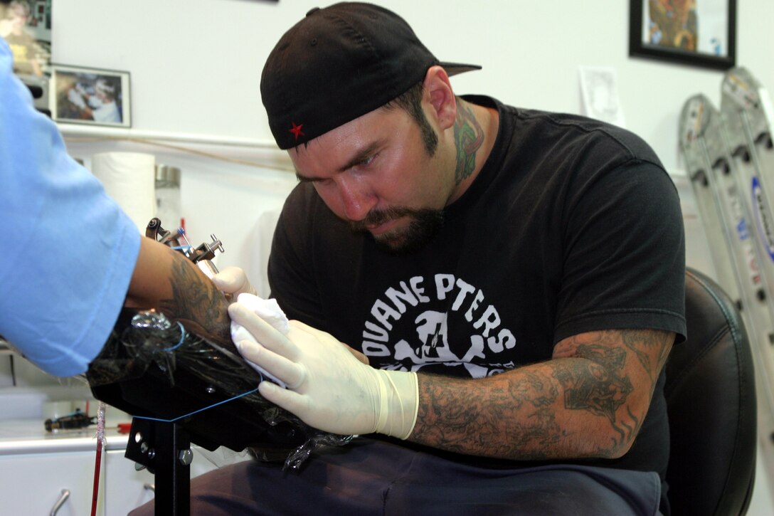 Tim W. Goodrich, tattoo artist at Odyssey Tattoo, works on a tattoo July 7. Goodrich, a former  Marine, feels the current regulations dealing with tattoos are good at how they are now and do not need to be changed.