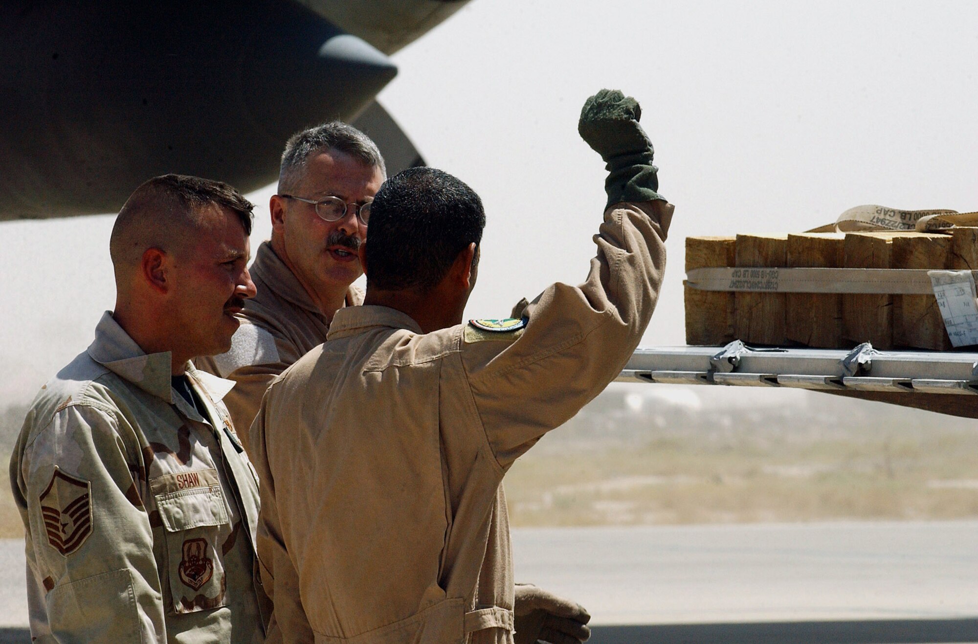 ALI BASE, Iraq -- Master Sgt. Patrick Shaw (left) and Senior Master Sgt. James Baarda instruct one of their Iraqi air force students (right) on the finer points of loading a C-130 Hercules.  The Airmen are part of a crew of more than 30 instructors teaching more than 100 Iraqi airmen how to fly and maintain C-130s here.  Sergeant Shaw is an aerial port instructor assigned to the 777th Expeditionary Aircraft Maintenance Squadron and is deployed from McChord Air Force Base, Wash.  Sergeant Baarda is a loadmaster instructor assigned to the 777th Expeditionary Airlift Squadron and is deployed from Yokota Air Base, Japan.  (U.S. Air Force photo by Airman 1st Class Jamie Shultz)