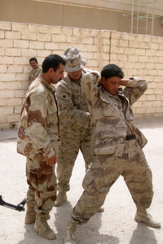 Marine Chief Warrant Officer Kenneth Silvers (center) shows an Iraqi Security Force soldier how to take down an uncooperative detainee during training exercises in Fallujah, Iraq, on July 3, 2005. Silvers and his fellow Marines from the 1st Battalion, 6th Marine Regiment are training Iraqi Security Forces in order to independently maintain control of Fallujah and surrounding provinces. 