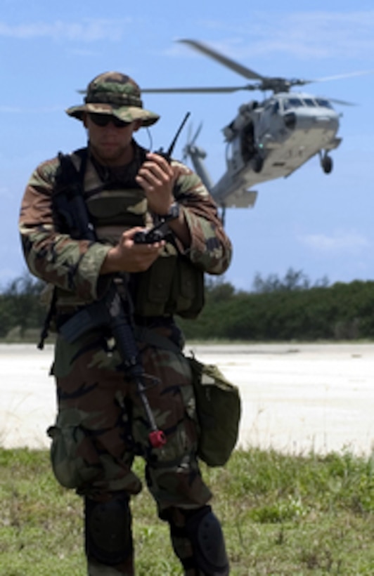 Navy Petty Officer 2nd Class Jackson J. Stasny listens to a call on his radio as a MH-60S helicopter prepares to land during an exercise at Naval Base Guam, Santa Rita, Guam, on June 30, 2005. Stasny is with the Mobile Security Squadron 7 Detachment 73, which is under going its pre-certification exercises before being officially examined to determine if it can be certified for deployment. 