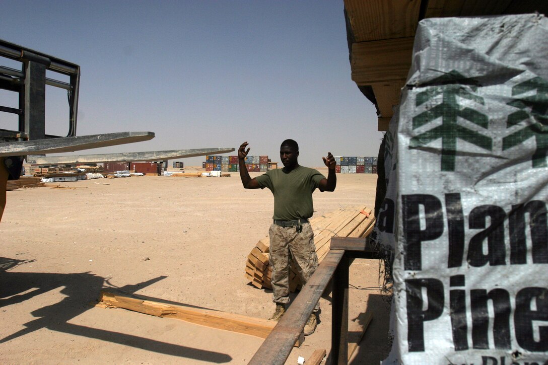 CAMP TAQADDUM, Iraq -- Lance Cpl. Anthony Murphy, a warehouse clerk with Supply Management Unit, Combat Logistics Regiment 25, 2d Force Service Support Group (Forward), directs a forklift to lift a bundle of wood.  Murphy, a Brooklyn, N.Y., native works in the class IV section of the SMU.