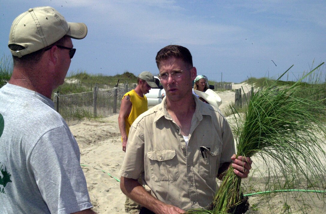 MARINE CORPS BASE CAMP LEJEUNE, N.C. - Marty Korenek (right) takes a break from planting sea oats to talk to Kevin Whaley about the success of the volunteer efforts with the Camp Lejeune Environmental Conservation Branch creating future sand dunes at Onslow Beach July 9. More than 30 volunteers gathered at Riseley Pier to plant 10,000 sea oat plants at various locations south of the pier in order to promote the preservation of Onslow Beach and hurricane protection. (Official Marine Corps photo by Lance Cpl. Matthew K. Hacker)