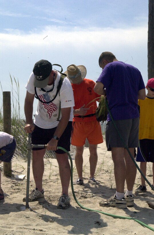 MARINE CORPS BASE CAMP LEJEUNE, N.C. - A volunteer with the Camp Lejeune Environmental Conservation Branch uses a metal pipe connected to a water hose to bore holes in the sand to house newly planted sea oats at Onslow Beach July 9. More than 30 volunteers gathered to help promote natural dune building with the by planting sea oats along the Onslow Beach coast. (Official Marine Corps photo by Lance Cpl. Matthew K. Hacker)