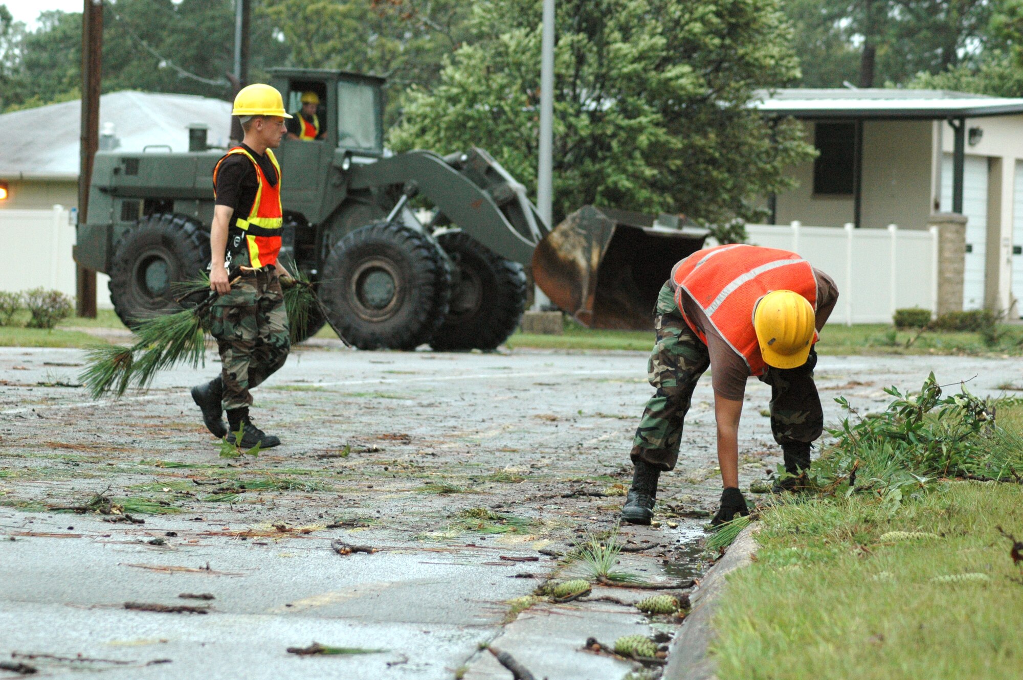 EGLIN AIR FORCE BASE, Fla. -- Airman 1st Class Brian Mikua (left) and Senior Airman Michael Rambaran pick up debris from fallen trees after Hurricane Dennis passed over here July 10.  The Airmen are assigned to the 796th Civil Engineer Squadron.  (U.S. Air Force photo by Senior Airman Mike Meares)