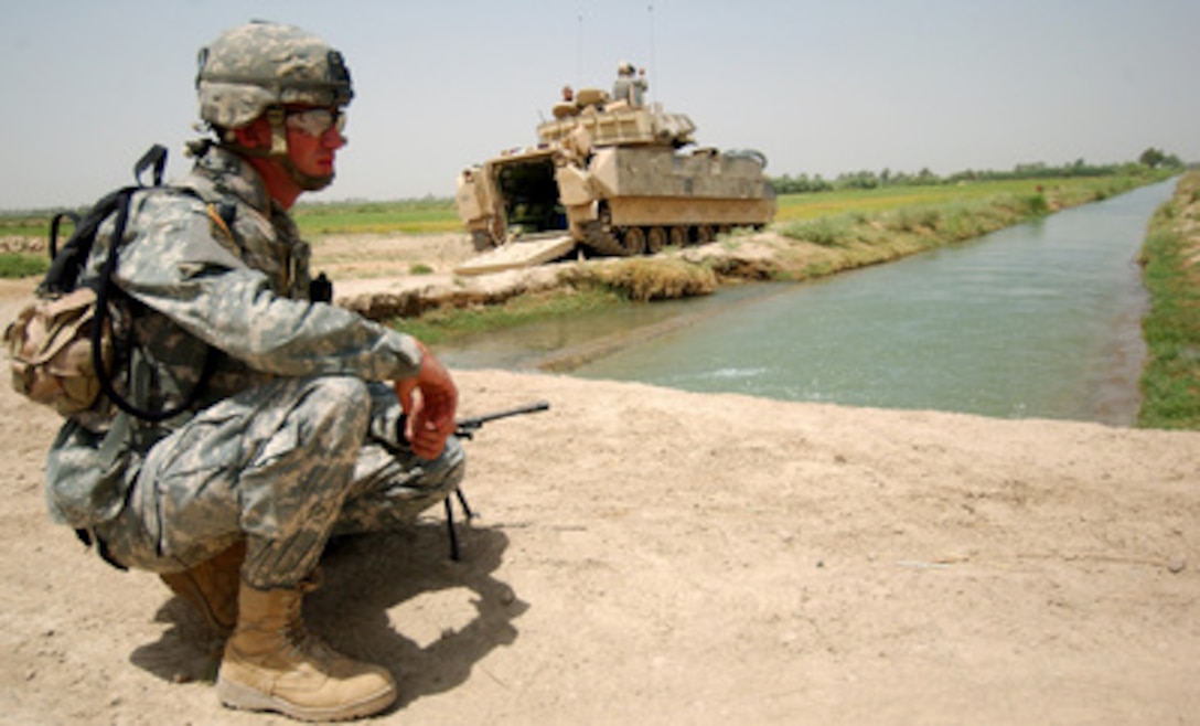 Army Spc. Eric Barrett watches for insurgent activity at a tactical control point along a canal near Al-Radwnea, Iraq, on July 6, 2005. Barrett and his fellow soldiers from Bravo Company, 2nd Battalion, 121st Infantry Regiment, and soldiers from the Iraqi National Guard are providing perimeter security while the U.S. Marines force insurgents out from nearby towns. 