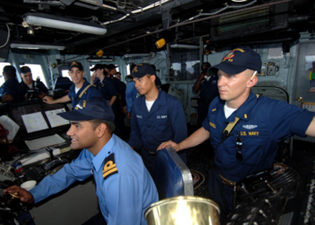 Pakistani Navy Lt. Muhammad Ali (left) controls the helm of the USS Hawes (FFG 53) under supervision of the Officer of the Deck Ensign Cromwell during Exercise Inspired Siren in the Arabian Sea on June 24, 2005. Inspired Siren is a joint U.S. and Pakistani Navy exercise in conducting Maritime Security Operations, air defense, anti-submarine warfare, surface warfare, mine counter measures, electronic warfare, replenishment at sea, and command and control. 