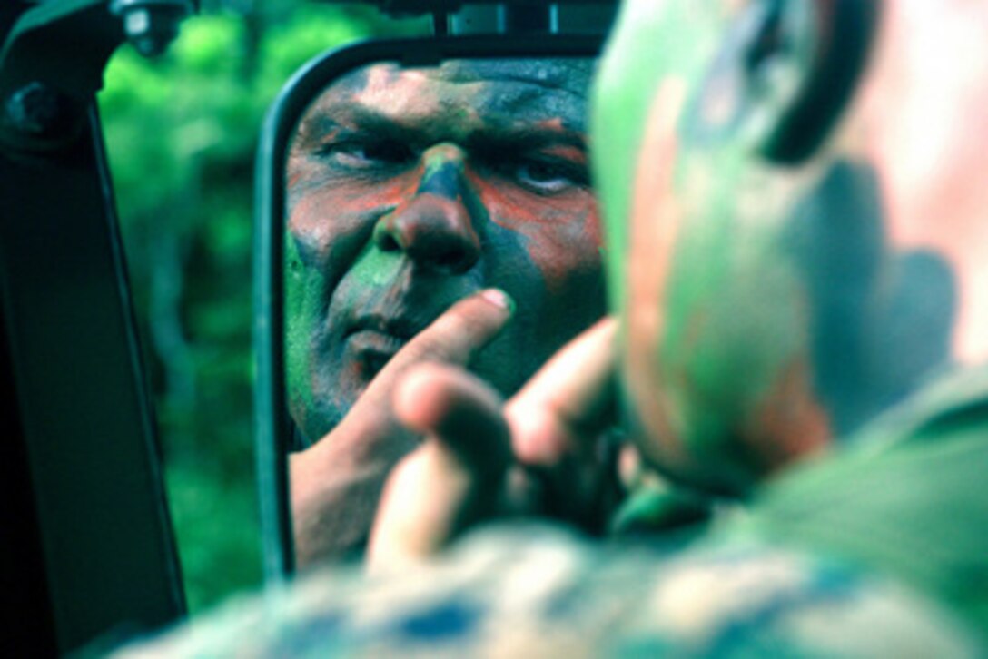 U.S. Marine Staff Sgt. Michael G. Walker applies camouflage face paint during a Rear Area Operations Field Exercise at the Central Training Area, Japan, on June 22, 2005. Ensuring proper application of the paint was one of the many concepts that were reinforced during the exercise. Walker is a maintenance chief with the Motor Transport Company, Headquarters Battalion, 3rd Marine Division. 