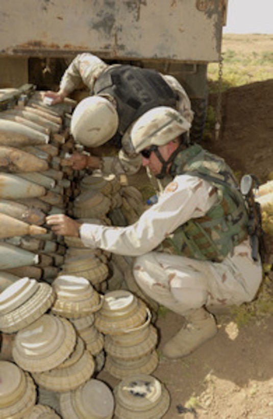 U.S. Army Sgt. 1st Class Shaun O'Connor carefully packs fuse holes on 120mm rounds with C4 explosives outside of Kirkuk Regional Air Base, Iraq, on July 10, 2005. U.S. Air Force and U.S. Army Explosive Ordnance Disposal team members are preparing over 2,500 pounds of seized ammunitions for demolition. O'Connor is attached to the Army's 116th Battalion Combat Team. 