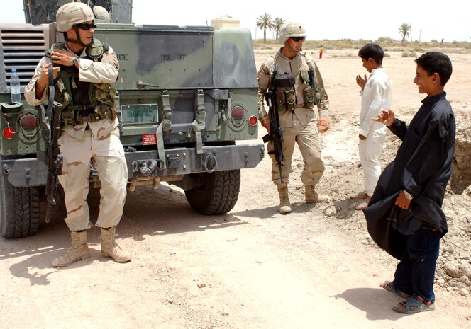 IRAQ -- Staff Sgt. Brian Czerniak (left) and his younger brother, Army Spc. Derek Czerniak, greet two locals during a recent patrol mission.  Specialist Czerniak, who is deployed to an undisclosed location in Iraq, jumped at the opportunity to visit Ali Base and watch his brother in action.  Sergeant Czerniak is a patrol leader with the 407th Expeditionary Security Forces Squadron and is deployed from Charleston Air Force Base, S.C.  Specialist Czerniak is an AH-64D Apache Longbow crew chief with the 2nd Battalion, 101st Aviation Regiment and is deployed from Fort Campbell, Ky.  (U.S. Air Force photo by Master Sgt. Maurice Hessel)