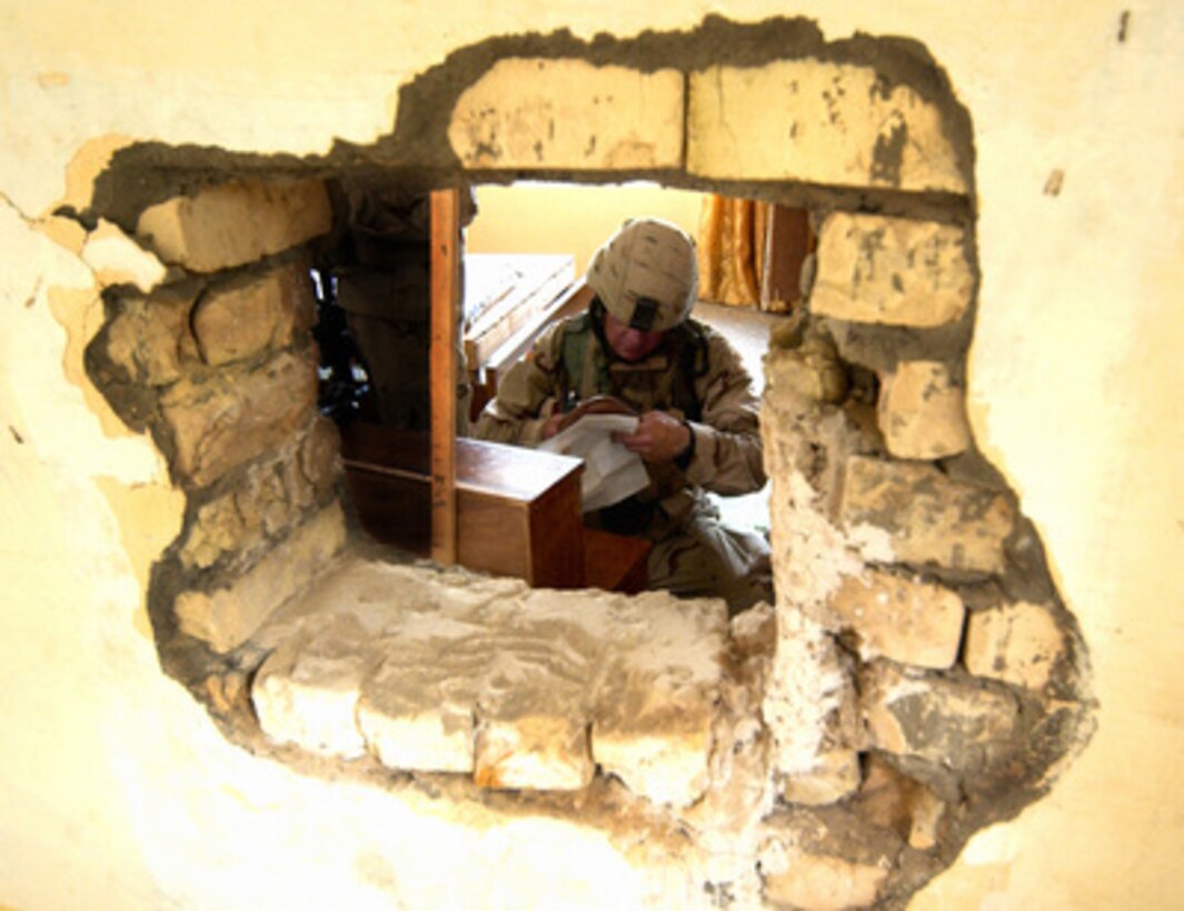 U.S. Army Spc. Arthur Huehl gathers evidence from a suspected terrorist cell leader's house in Taji, Iraq, on July 5, 2005. Iraqi Army and Coalition Forces conducted the raid on the house after an informant notified authorities of the location of the terrorist leader. Huehl is attached to Bravo Company, 1st Battalion, 13th Armor Regiment, 3rd Brigade, 1st Armored Division. 