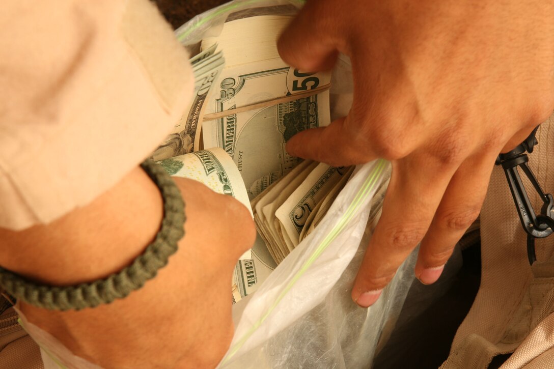 CAMP GANNON, Iraq (May 17, 2007) ? Lance Cpl. Jay A. Marcus searches through a bag of money to find bills amounting to a Marine?s request. The Exchange and disbursing Marines travel to Al Qaim?s neighboring forward operating bases to provide service to servicemembers there. Marcus is a disburser and a Coral Springs, Fla., native.