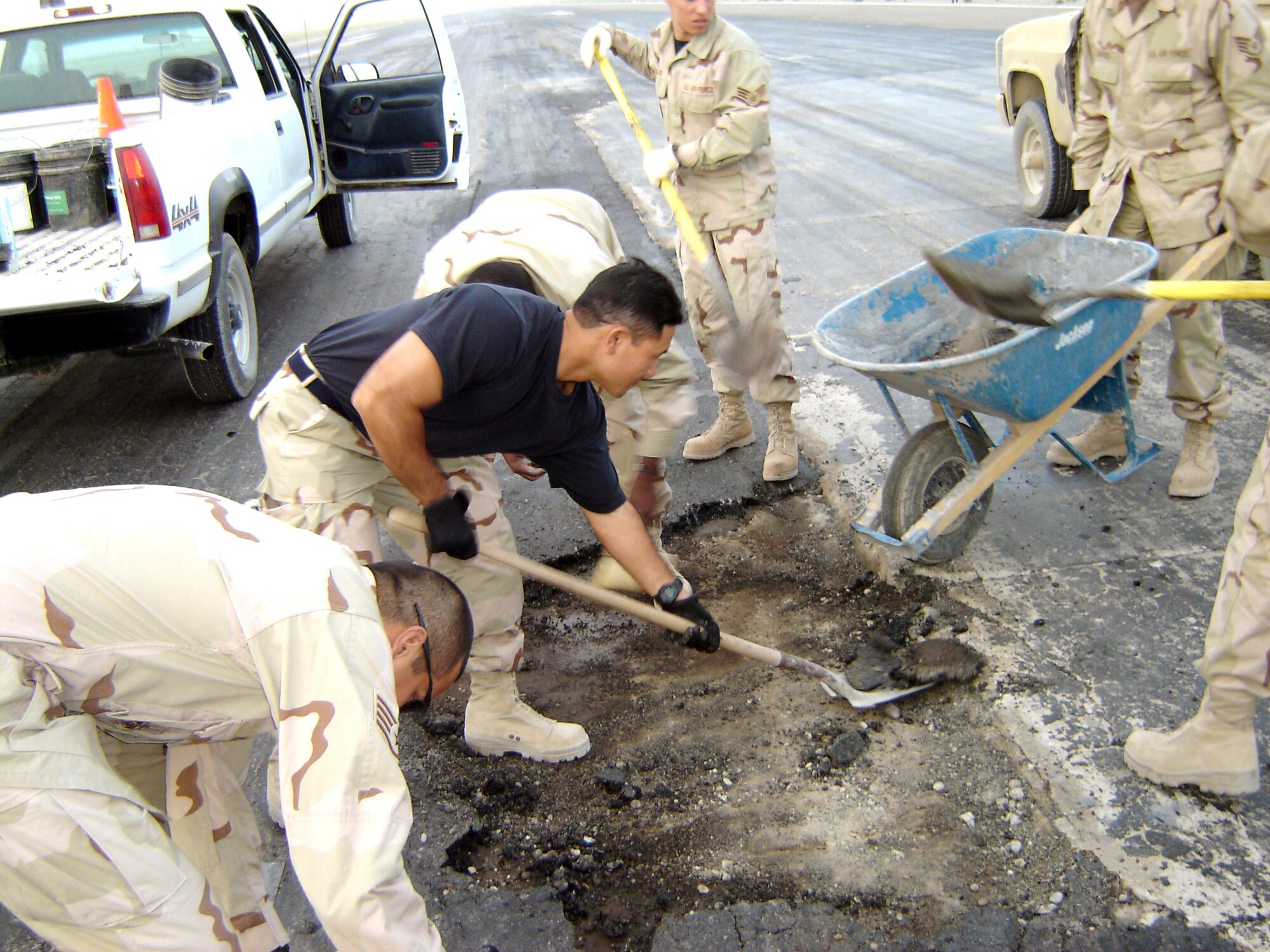 KANDAHAR AIRFIELD, Afghanistan -- Capt. Reid Matsuda shovels a runway spall.  The 40-year-old airfield requires constant upkeep to ensure that heavy aircraft can land and resupply here.  Captain Matsuda is assigned to the 451st Civil Engineer Group.  (U.S. Air Force photo by Senior Airman James Fisher)
