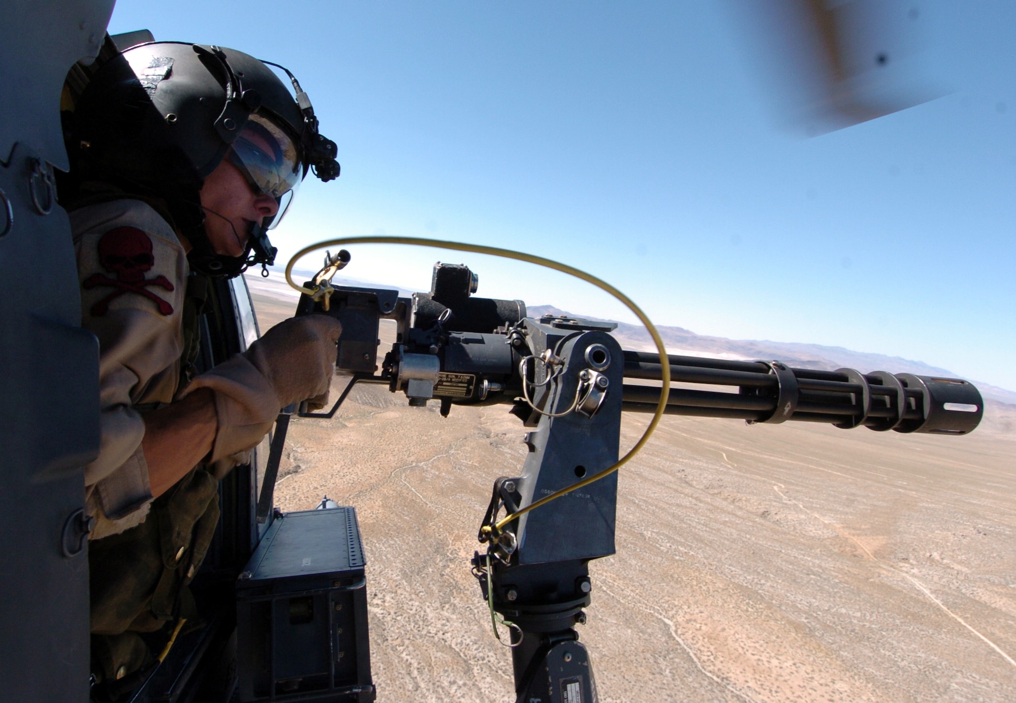 OVER FALLON, Nev. -- Airman 1st Class Melody Boates simulates firing a 7.62 mini-gun from an HH-60G Pave Hawk during exercise Desert Rescue here July 12. Desert Rescue is a multi-service, multi-national training exercise held annually to prepare combat search and rescue teams. Airman Boates is assigned to the 41st Rescue Squadron at Moody Air Force Base, Ga. (U.S. Navy photo by Petty Officer 3rd Class Rebecca J. Moat)

