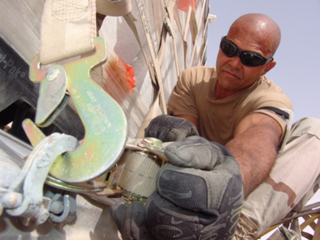 Air National Guard Tech. Sgt. Carlos De Los Santos secures and tightens a cargo strap on a cargo pallet before being loaded on a C-17 Globemaster III aircraft destined for Iraq on July 11, 2005. De Los Santos is deployed from the 111th Fighter Wing, Willow Grove, Pennsylvania Air National Guard. 