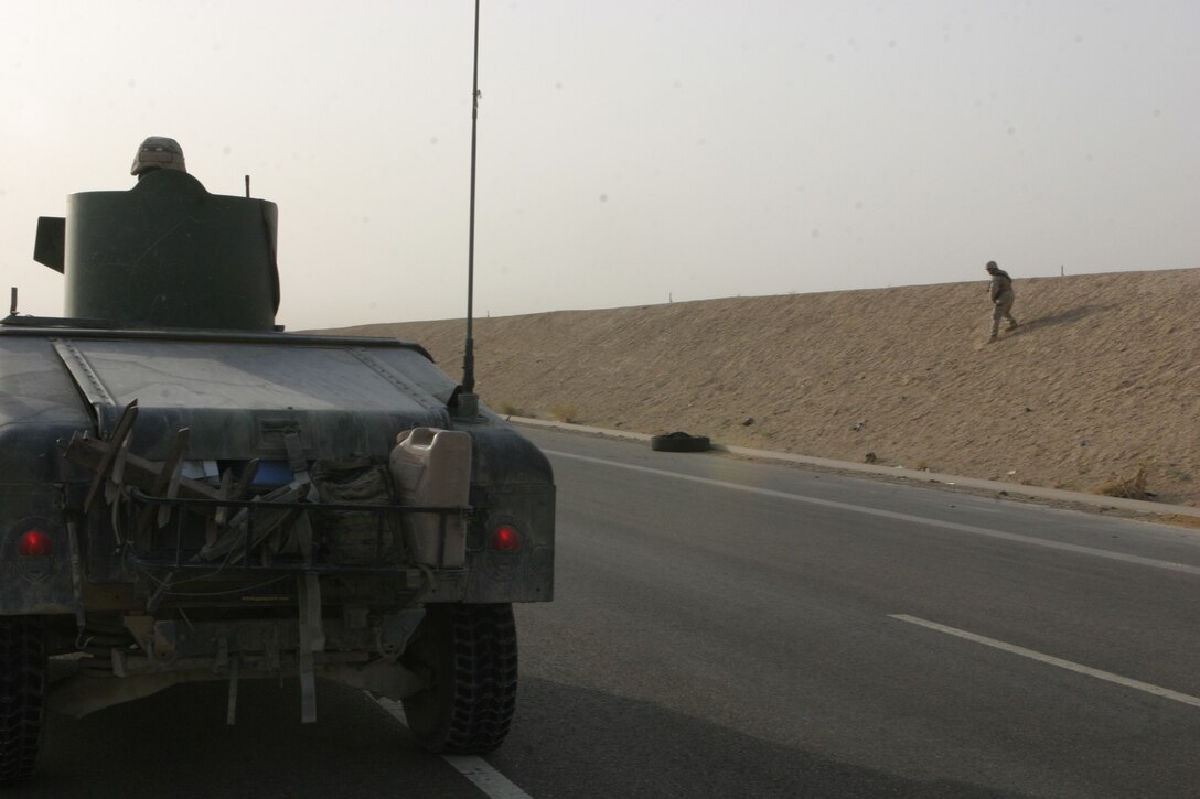 CAMP FALLUJAH, Iraq – Marines with Military Police Detachment, Combat Logistics Battalion 8, 2d Force Service Support Group (Forward), stop to investigate debris on the side of the road while conducting security patrols here. The debris, a possible hiding place for Improvised Explosive Devices, was removed without incident. The MPs conduct security patrols along certain major roadways in the Fallujah area to eliminate the insurgent threat and ensure safe passage for Coalition Forces. (Photo by Cpl. John E. Lawson Jr.)