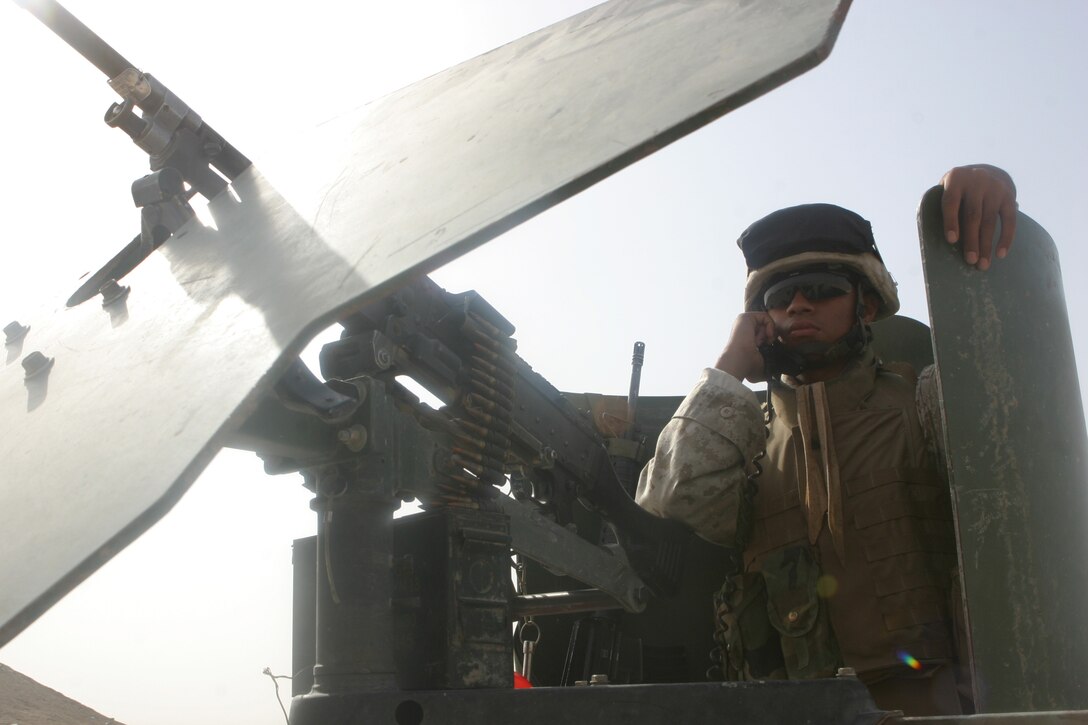 CAMP FALLUJAH, Iraq – Corporal Rolando F. Layda, a Santa Clara, Calif., native and motor transport vehicle operator supporting Military Police Detachment, Combat Logistics Battalion 8, 2d Force Service Support Group (Forward), uses monitors communications equipment while behind his M240-G medium machinegun during a security halt while patrolling roadways in the Fallujah area. The MPs conduct these security patrols along certain major roadways to eliminate any insurgent threat and ensure safe passage for Coalition Forces. (Photo by Cpl. John E. Lawson Jr.)