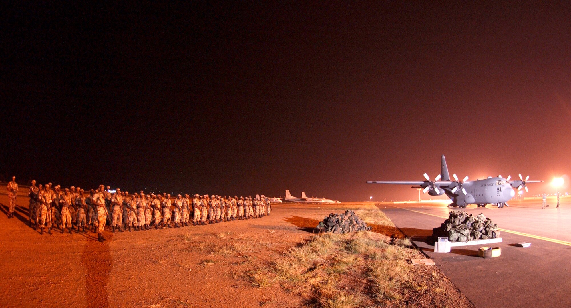 KIGALI INTERNATIONAL AIRPORT, Rwanda -- Rwandan forces stand by to board a C-130 Hercules from Ramstein Air Base, Germany, here July 19. The Ramstein Airmen were here to provide transportation for 1,200 Rwandan forces to Sudan in support of NATO's response for the African Union's expanded peacekeeping mission in Darfur with logistics and training.  (U.S. Air Force photo by Staff Sgt. Bradley C. Church)