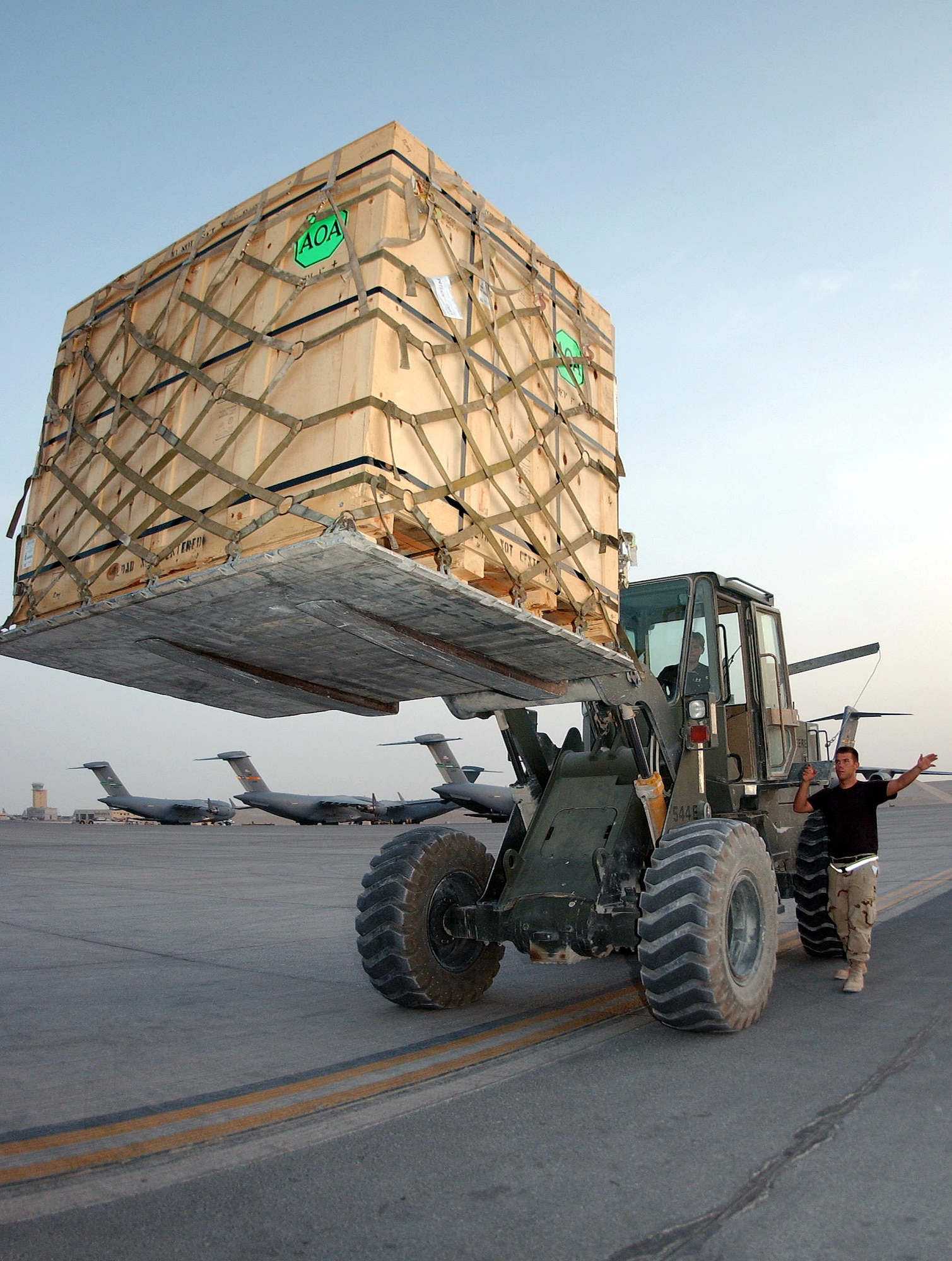 SOUTHWEST ASIA -- Airman 1st Class Adam Dix guides Senior Airman Heidi Gould as she loads an up-armor kit pallet using a 10-ton loader July 19.  The Airmen are assigned to the 8th Expeditionary Air Mobility Squadron at a forward-deployed location.  (U.S. Air Force photo by Airman 1st Class Desiree Hayden)
