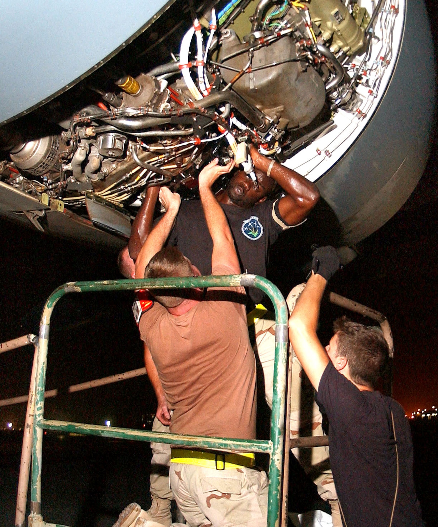 SOUTHWEST ASIA -- Staff Sgt. Rushad Stroman (center) get help from (from left) Airman 1st Class Gatlin Rowland and Senior Airman Matt Smith as they replace an integrated drive generator in a C-17 Globemaster III engine.  The C-17s fly around-the-clock to get Humvees and up-armor kits to forward-deployed Soldiers and Marines.  The Airmen are maintainers with the 8th Expeditionary Air Mobility Squadron at a forward-deployed location.  (U.S. Air Force photo by Airman 1st Class Desiree Hayden)