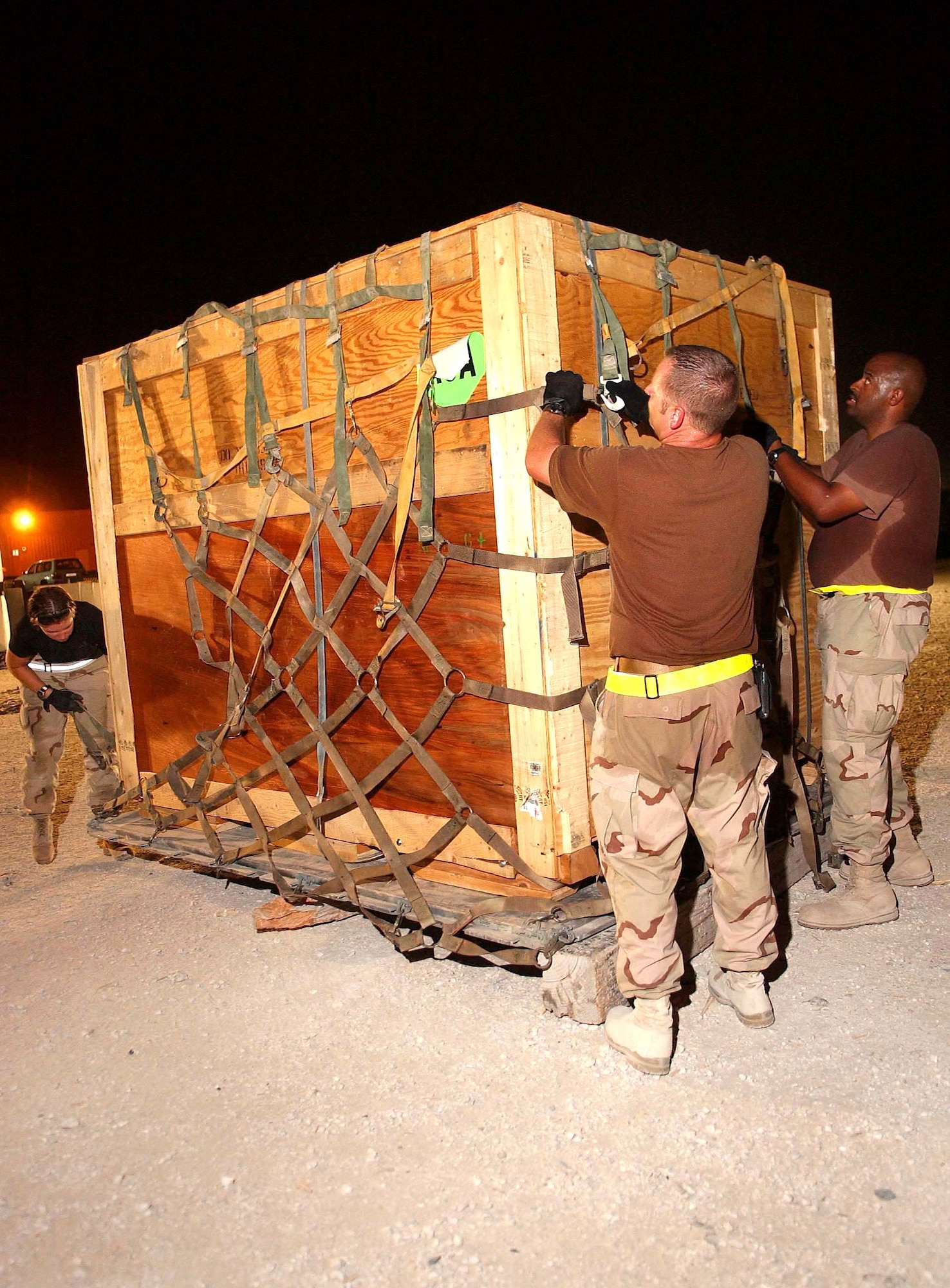 SOUTHWEST ASIA -- (From left) Staff Sgt. Naomi Groom, Tech. Sgt. Mason McGill and Master Sgt. Antonio Brock secure the latest in the series of 275 up-armor kit pallets July 19 scheduled for shipment to forward-deployed Soldiers and Marines on July 19.  Working around-the-clock at a forward-deployed location, 8th Expeditionary Air Mobility Squadron Airmen expect to complete shipment of all pallets in five days.  (U.S. Air Force photo by Airman 1st Class Desiree Hayden)