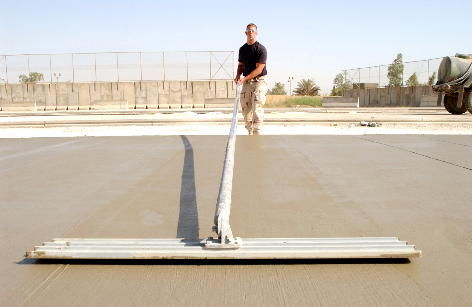 BAGHDAD, Iraq -- Staff Sgt. Jason Hanson uses a bull float to finish concrete at the main entry control point for the Baghdad International Airport complex that will be used to improve security for civilians and coalition forces.  He is deployed to the 557th Expeditionary Red Horse Squadron from Schriever Air Force Base, Colo.  (U.S. Air Force photo by Tech. Sgt. Brian Davidson) 