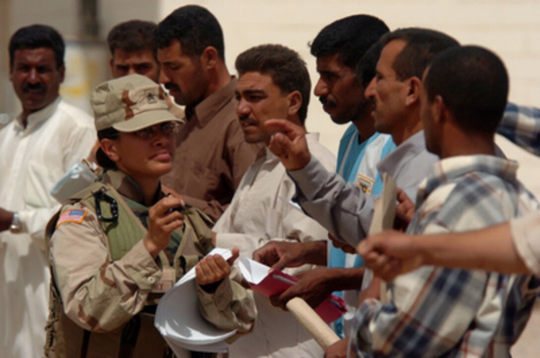 U.S. Army Sgt. Amber Aki helps Iraqi men as they prepare to take a physical readiness test in Iskandariyah, Iraq, during the initial screening for selection to the Iraqi Police Training Academy on July 8, 2005. The screening is being held at the Iraqi Army compound and is being conducted by the Iraqi Army, Iraqi Police forces, and U.S. soldiers. Aki is attached to Bravo Company, 490th Civil Affairs Battalion, 155th Brigade Combat Team. 