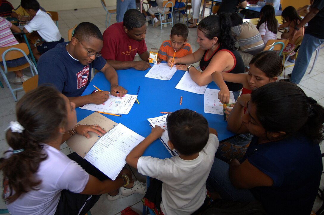 MANTA, Ecuador -- (From left) Senior Airman Darious Harper and Senior Master Sgt. Michael Anderson help children with their homework. Airman Darius is an information manager at the nearby base, and Sergeant Anderson is the first sergeant. (U.S. Air Force photo by Master Sgt. Efrain Gonzalez)