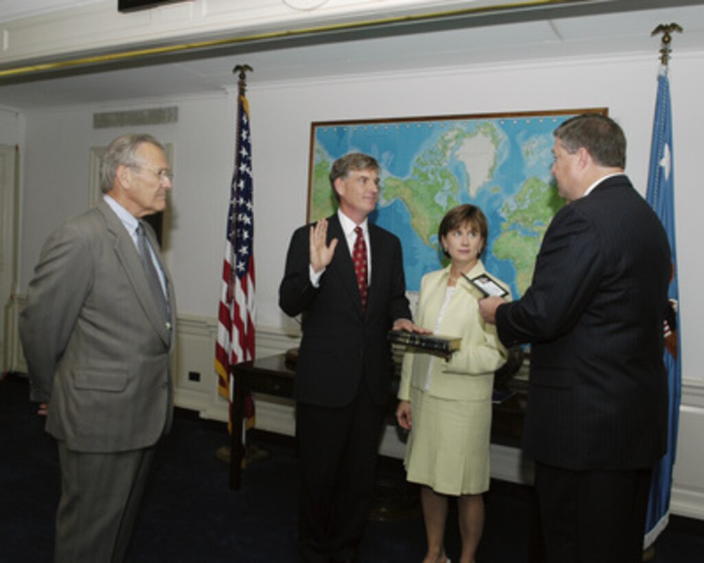 Secretary of Defense Donald H. Rumsfeld (left) looks on as Ken Krieg (center) takes the oath of office as Under Secretary of Defense for Acquisition, Technology and Logistics on July 20, 2005. Mrs. Anne Krieg holds the bible as the oath is administered by the Director of Administration and Management Michael Donley. The ceremony was held in Rumsfeld's office in the Pentagon. 
